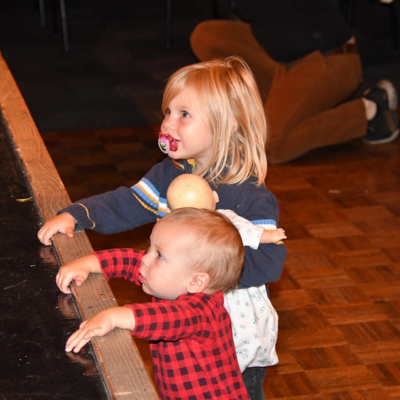 Two small children standing at the edge of a stage