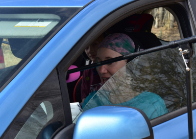 A woman in the driver's seat in front of a microphone wearing headphones.