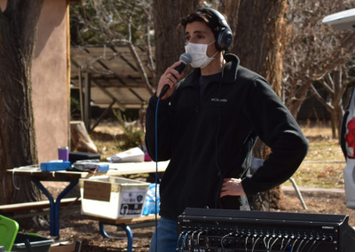 A masked engineer standing at a soundboard outside.