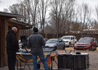 A view of the engineering table with two men standing in front of soundboards while cars are on a grid in the field in the background beyond the soundboard table.