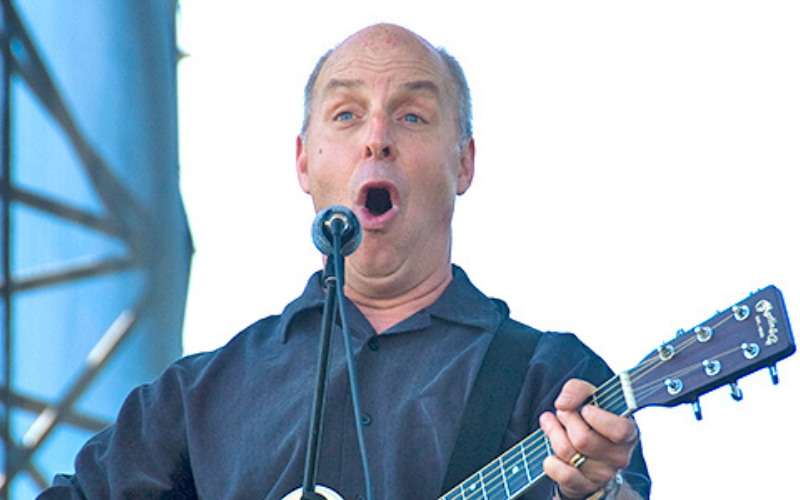 Dr. Jerry Dragoo is nose to nose with a striped skunk, smiling. 