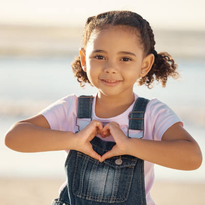 A little girl holding her hands in the shape of a heart.